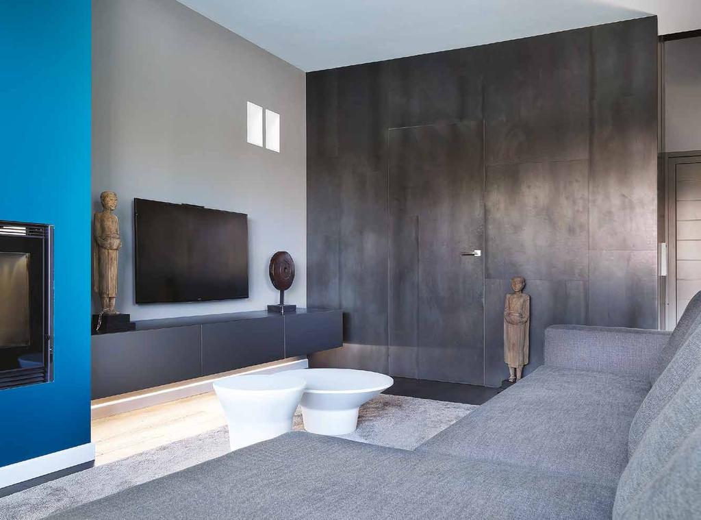 66 Volumi puliti ed equilibri cromatici compongono l area dedicata al living, delimitata su un lato da un rivestimento in lamiera, che mimetizza la porta del bagno