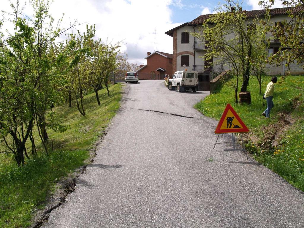 FOTOGRAFICI Immagine 01-2019/04/02-Carreggiata stradale deformata dal movimento franoso; sullo sfondo la