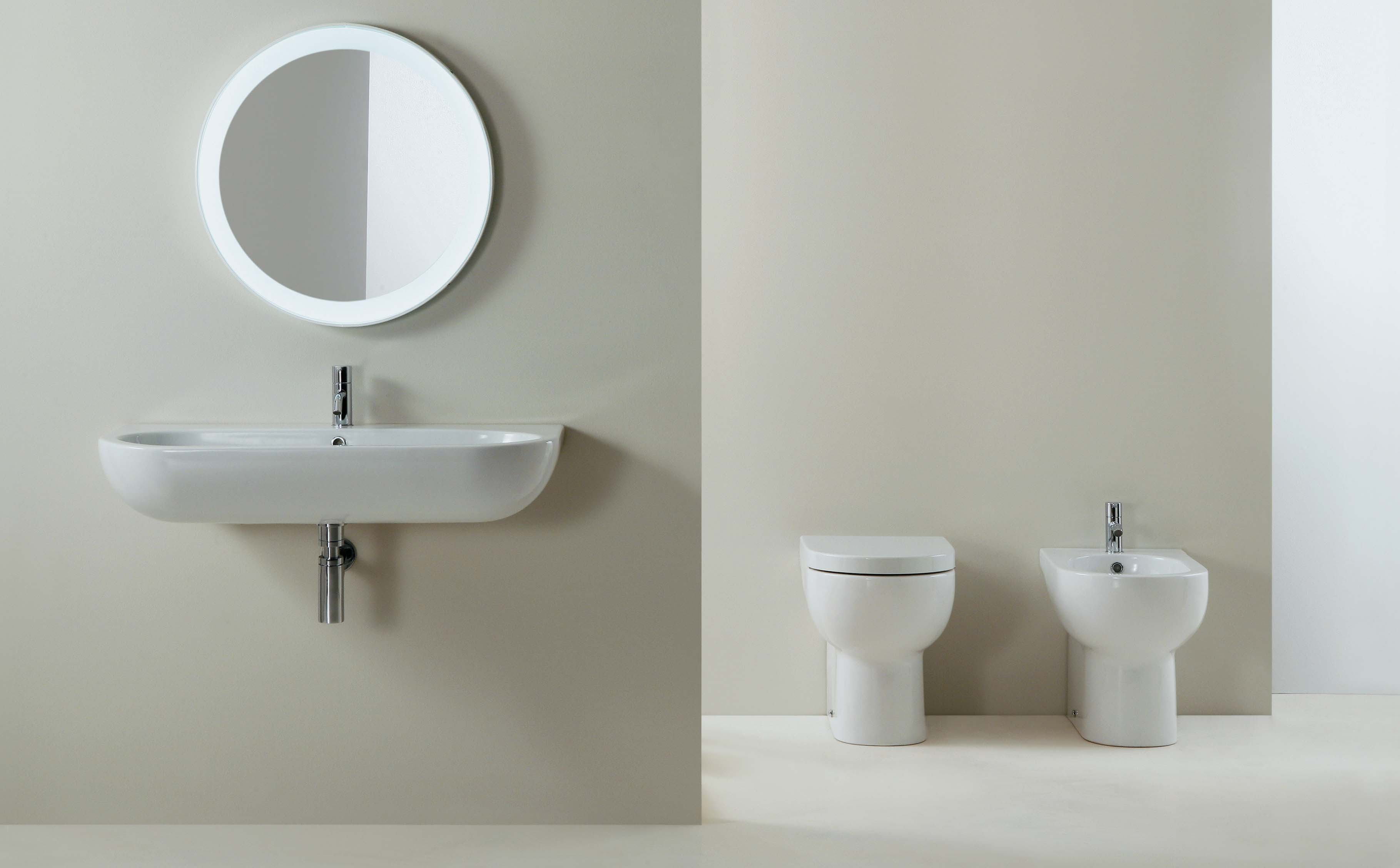 Lavabo sospeso monoforo cm 90x45. Specchio Tondo cm 60 con luce perimetrale interna. Vaso e bidet monoforo.