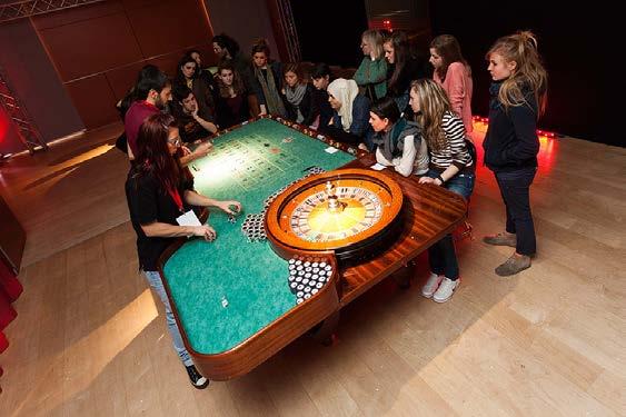 Fate il nostro gioco mostra interattiva sulla matematica del gioco d azzardo proposta didattica_ Un gruppo di ragazzi è seduto attorno al tavolo verde della roulette e segue la pallina rimbalzare in