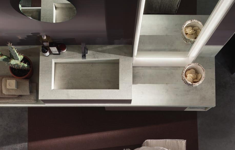 La cornice luminosa dello specchio mette in luce il design dell ambiente bagno, mentre il top condivide la sua matericità con il lavabo integrato.