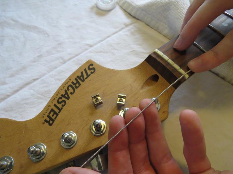 Passo 5 Posare la stringa parallela al collo della chitarra e direttamente sopra la chiave di