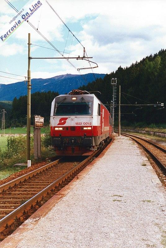 I pochi viaggiatori possono attendere il treno al fresco sotto gli alberi prima di portarsi sul marciapiede riarso dal