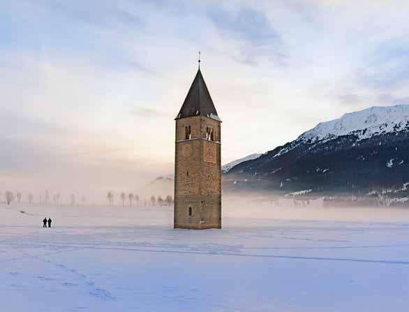 Meran In inverno il ghiaccio abbraccia scricchiolante il campanile sommerso nel lago di Resia, mentre le montagne circostanti proteggono le silenziose valli laterali offrendo uno scenario invernale