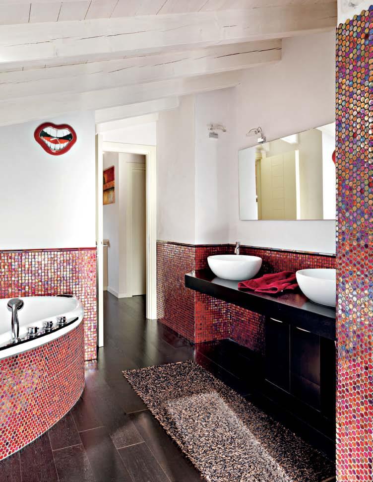 Un mosaico Bisazza multicolore decora la sala da bagno, con vasca idromassaggio e una coppia di lavandini su piano in wengé (Far Arreda).
