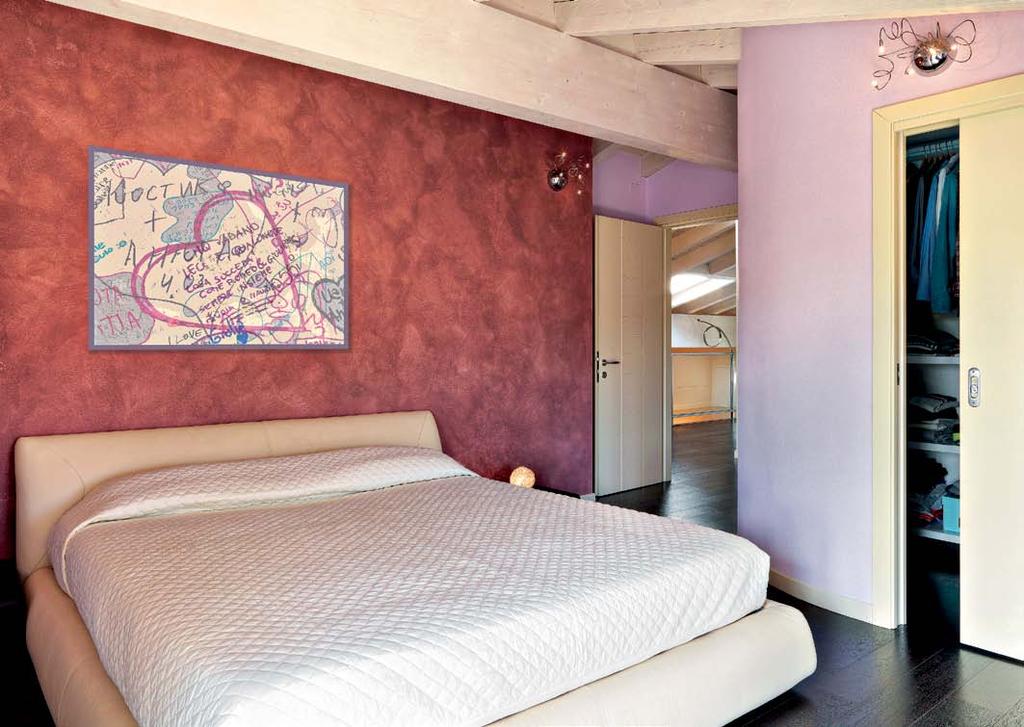 Sopra: una parete in velatura color melanzana incornicia il letto in pelle, unico elemento della camera padronale, organizzata accanto a una capiente cabina-guardaroba, fornita di cassettiere e
