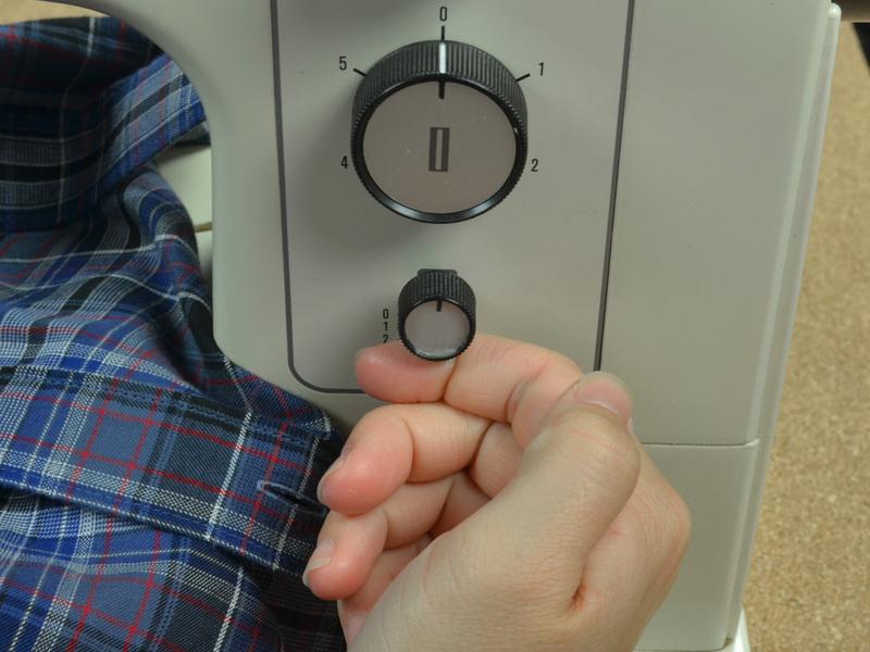Il sistema di selezione del punto indietro varia molto da una macchina da cucire all'altra e può essere presente sotto forma di pulsante, leva o manopola.