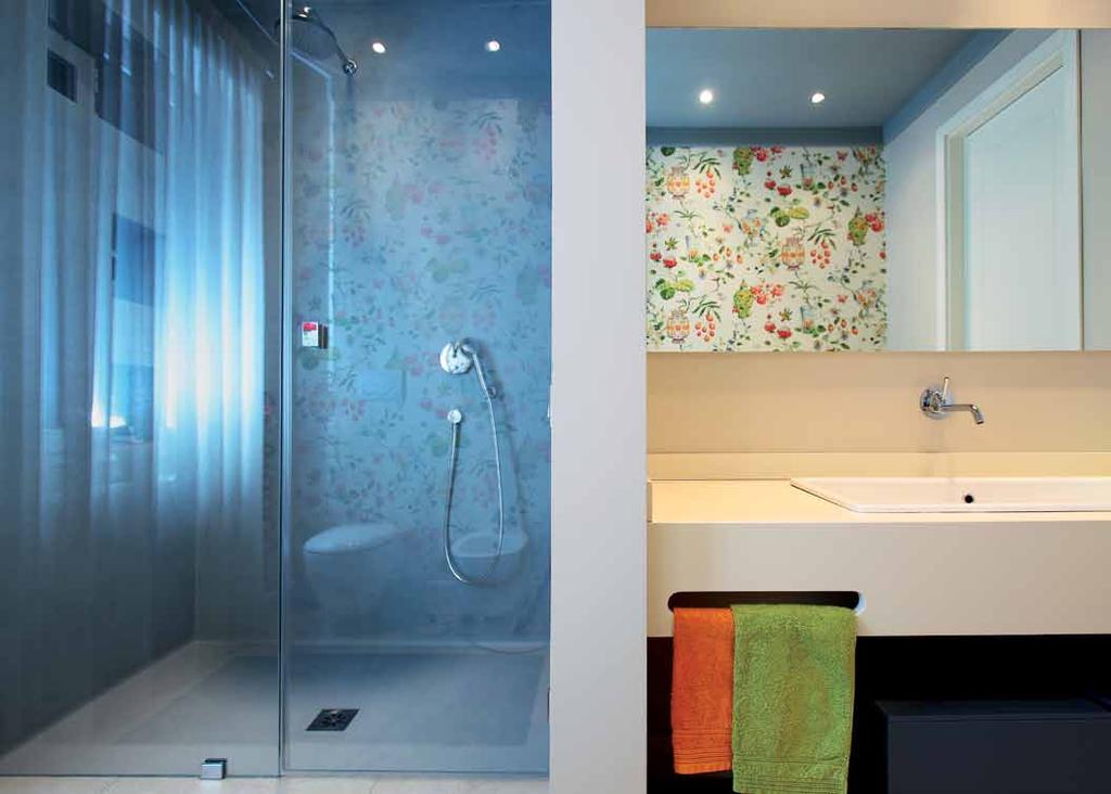 Nel secondo bagno una parete regolare separa l ampia doccia dallo spazio attrezzato come fosse una lama; piatto doccia in resina azzurro polvere; mobile del lavello laccato realizzato con un intaglio