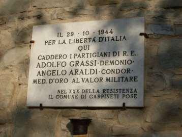 In Memoria di Adolfo Grassi e Angelo Araldi si tratta di una lapide in marmo bianco sostenuta da fermi metallici e con epigrafe in rilievo.