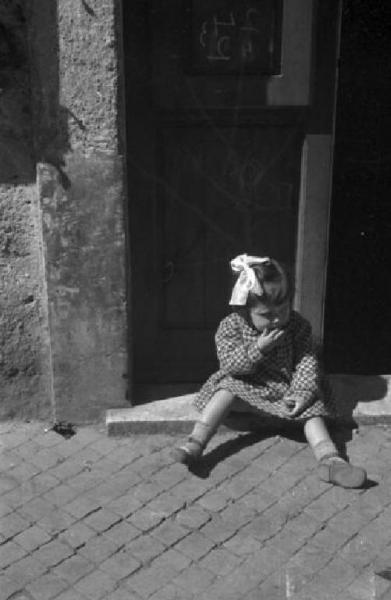 Castel Gandolfo. Scene di vita quotidiana - bambina seduta davanti a un portone si guarda attorno. Patellani, Federico Link risorsa: http://www.