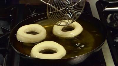 una capiente padella dell'olio di semi per friggere, tuffate le ciambelle in frittura