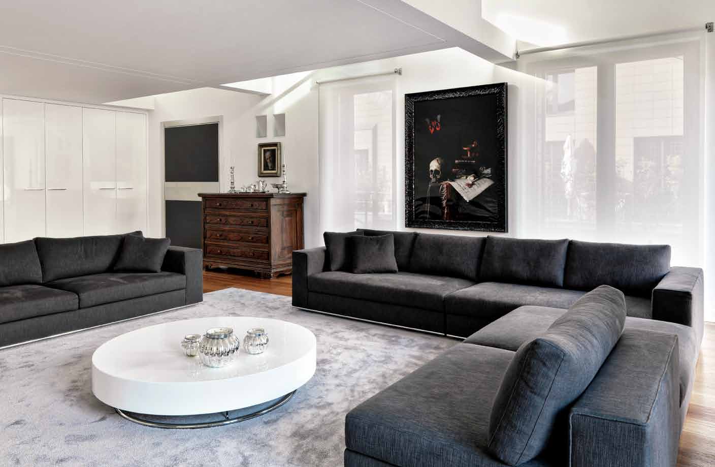 Veduta del soggiorno con divani in tessuto nero in contrapposizione al bianco ottico delle pareti, del grigio del tappeto e del mobile