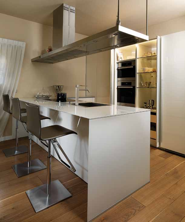 Cucina minimalista con penisola a cassettoni, in vetro bianco laccato lucido, adibita a bancone.