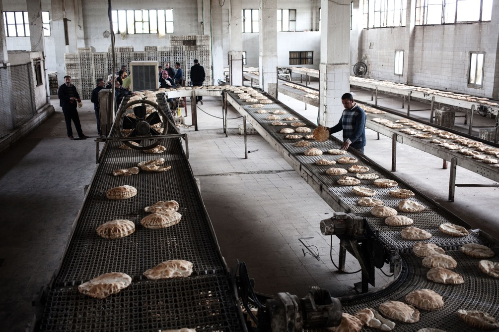 Morbidi dischi di pane azzimo appena sfornati, ancora gonfi e bollenti, scorrono ordinatamente su un nastro di ferro