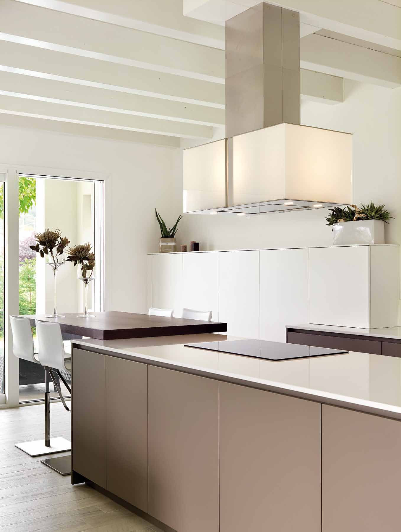 Visione prospettica dello spazio cucina: ad incasso la composizione a colonne laccata bianco opaco con elettrodomestici in acciaio.