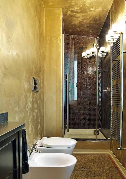 Il bagno moderno con tinteggiatura in oro a stucco che si abbina al rivestimento Bisazza dorato della doccia.