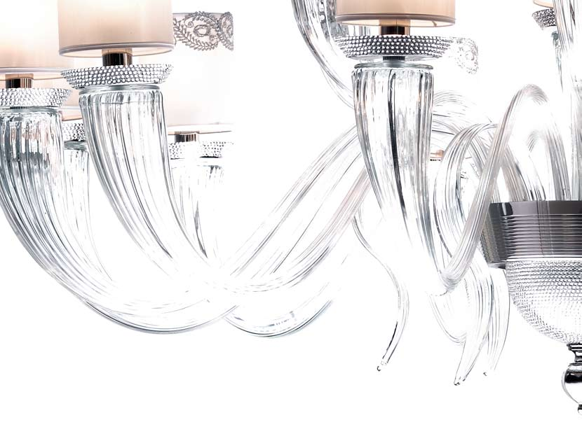 Lampadario in vetro di Murano trasparente e bobeches in ottone cromato con incastonati Swarovski Elements; paralumi in seta bianca lucida e passamaneria barocca argento.