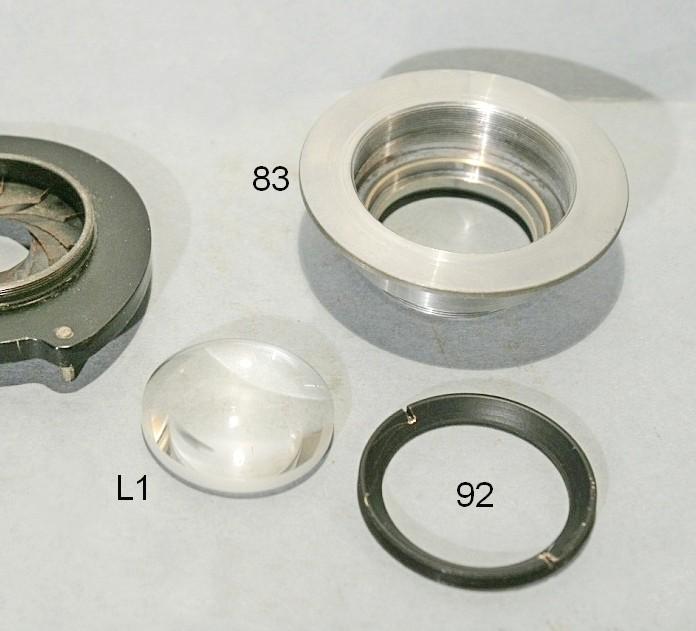 Il porta-filtri 86 è imperniato sul cilindretto 89, fissato al lato inferiore del pezzo 84 dalla vite 87; la rondella 88, che sta sotto la testa della vite 87, è elastica, a