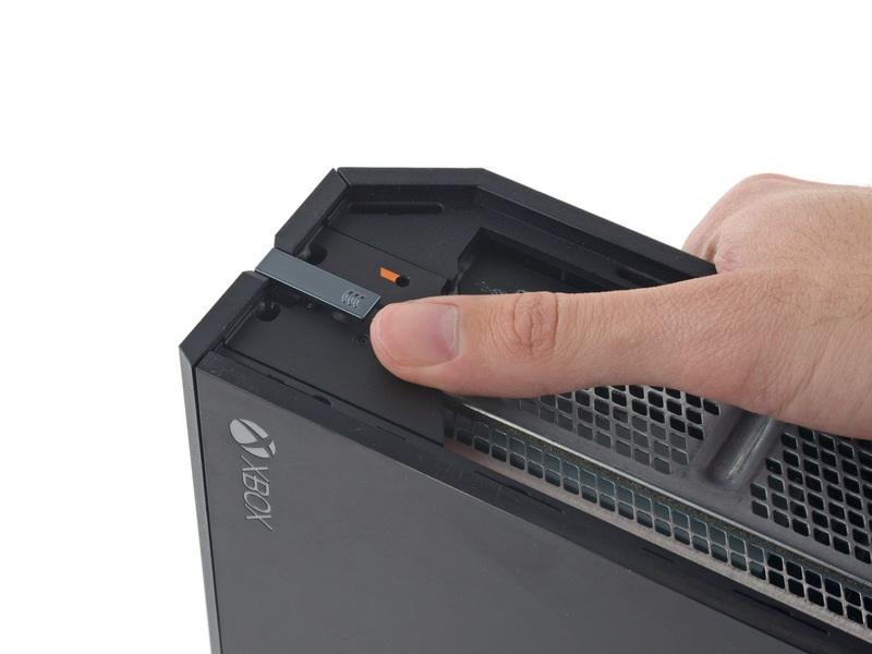 Passo 3 C'è una linguetta di plastica che rafforza l'angolo anteriore della console Xbox.