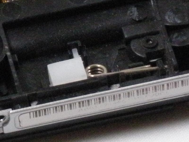Passo 9 Con il lato anteriore della PSP rivolto verso di sé, individuare piccola scatola di plastica bianca con molla di metallo attaccato.