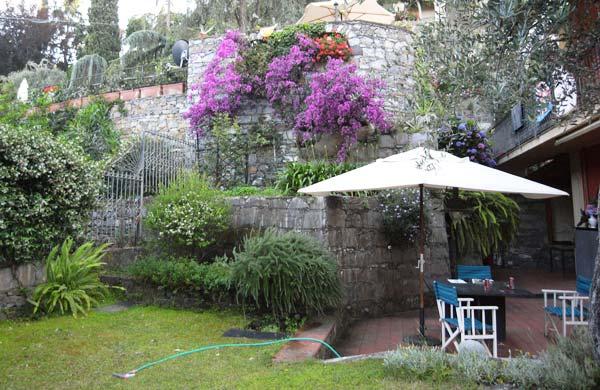 La foto mostra il giardino con grande tavolo in ardesia e l ombrellone per l utilizzo estivo.