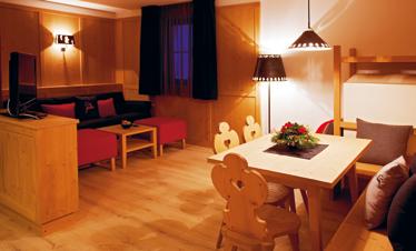 Residence 4-5 PERSONE 60 m 2 Sigrid Spazioso soggiorno con comodo divano letto, angolo cucina e angolo pranzo in stile tirolese, stufa tirolese con panca e balcone.