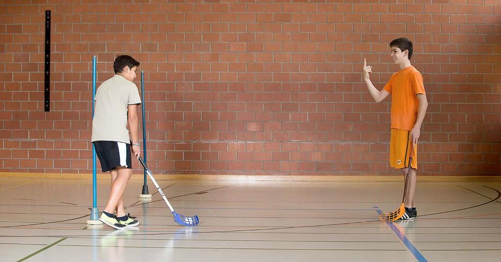 Matematica e unihockey Un bambino cerca di dribblare la pallina mentre il compagno gli mostra diversi numeri con le dita.