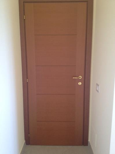 Le porte interne degli alloggi, di dimensioni cm 70-80 x 210, sono tamburate, cieche, lisce, colore legno scuro, dello spessore di 45mm, complete di maniglie di acciaio cromo satinato e serratura.