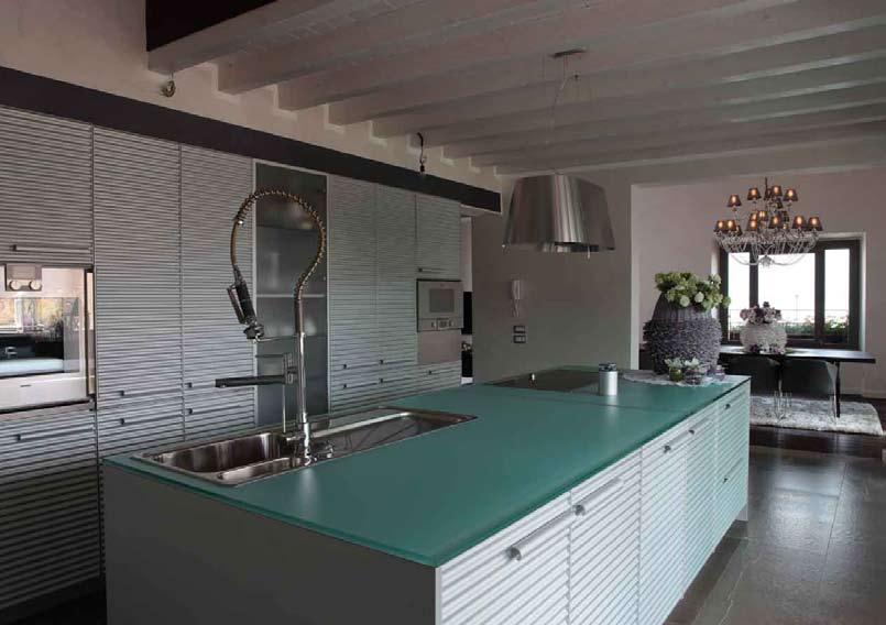 Nota glamour con il lampadario con paralumi satin e gocce di Swarovski Sopra: la cucina Cinqueterre di Schiffini realizzata in alluminio, con top in vetro e attrezzata con elettrodomestici Gaggenau è