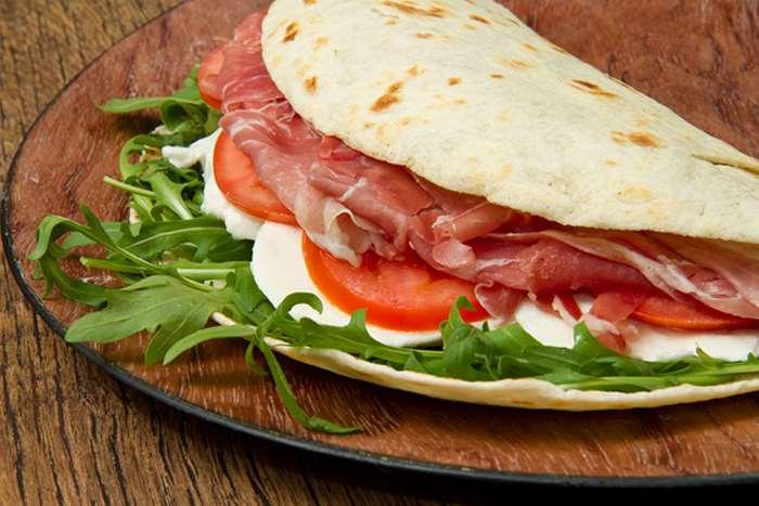 Piadina romagnola La Piadina o Piada è un pane antico, risalente al periodo dei Romani, e conservato ancora nelle tradizioni della Romagna, tanto da esserne il simbolo enogastronomico.