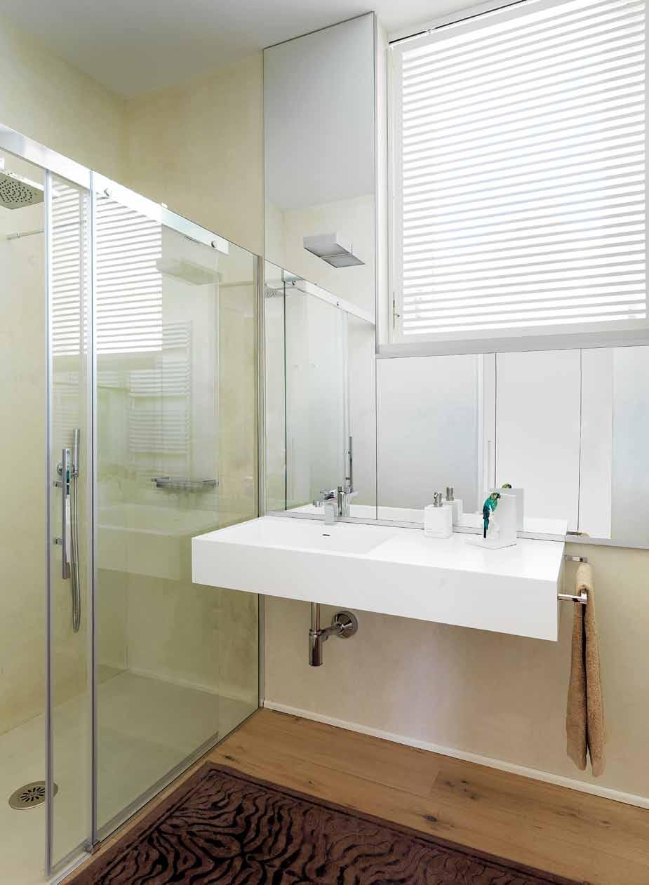 Bagno elegante e luminoso, con lavandino minimale sospeso e maxi doccia con rivestimento interno in resina. Uno specchio incornicia la finestra (progetto d interni Far Arreda).