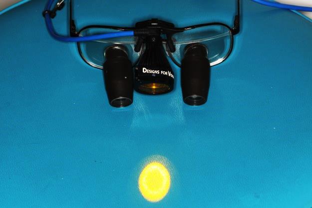 A sinistra: gli occhiali con sistemi di ingrandimento, e la luce da fibra ottica. A destra: la sonda parodontale millimetrata: si vedono in nero segnate le tacche dei 5, 10 e 15 millimetri.