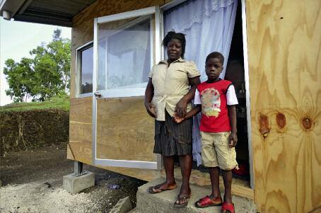 Foto: CRS, Florian Kopp La ricostruzione avanza. Questa madre e suo figlio avevano perso la loro abitazione nel terremoto. Eccoli davanti alla loro nuova casa, a Palmiste-à-Vin. più presto.