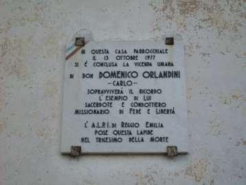 In Memoria di Don Domenico Orlandini In marmo e con epigrafe in rilievo, la lapide presenta nell'angolo in alto a destra due diagonali di colore rosso e verde.