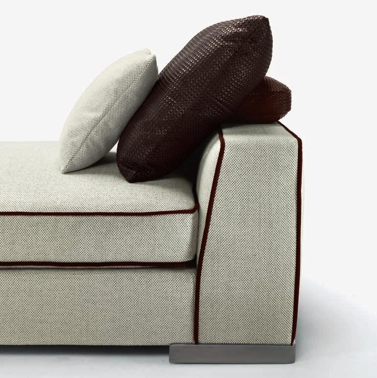 La morbida silhouette del divano Armand è sottolineata dalla confezione sartoriale dei profili che rifiniscono braccioli e cuscini, per i quali si può scegliere un ricercato profilo in gros grain